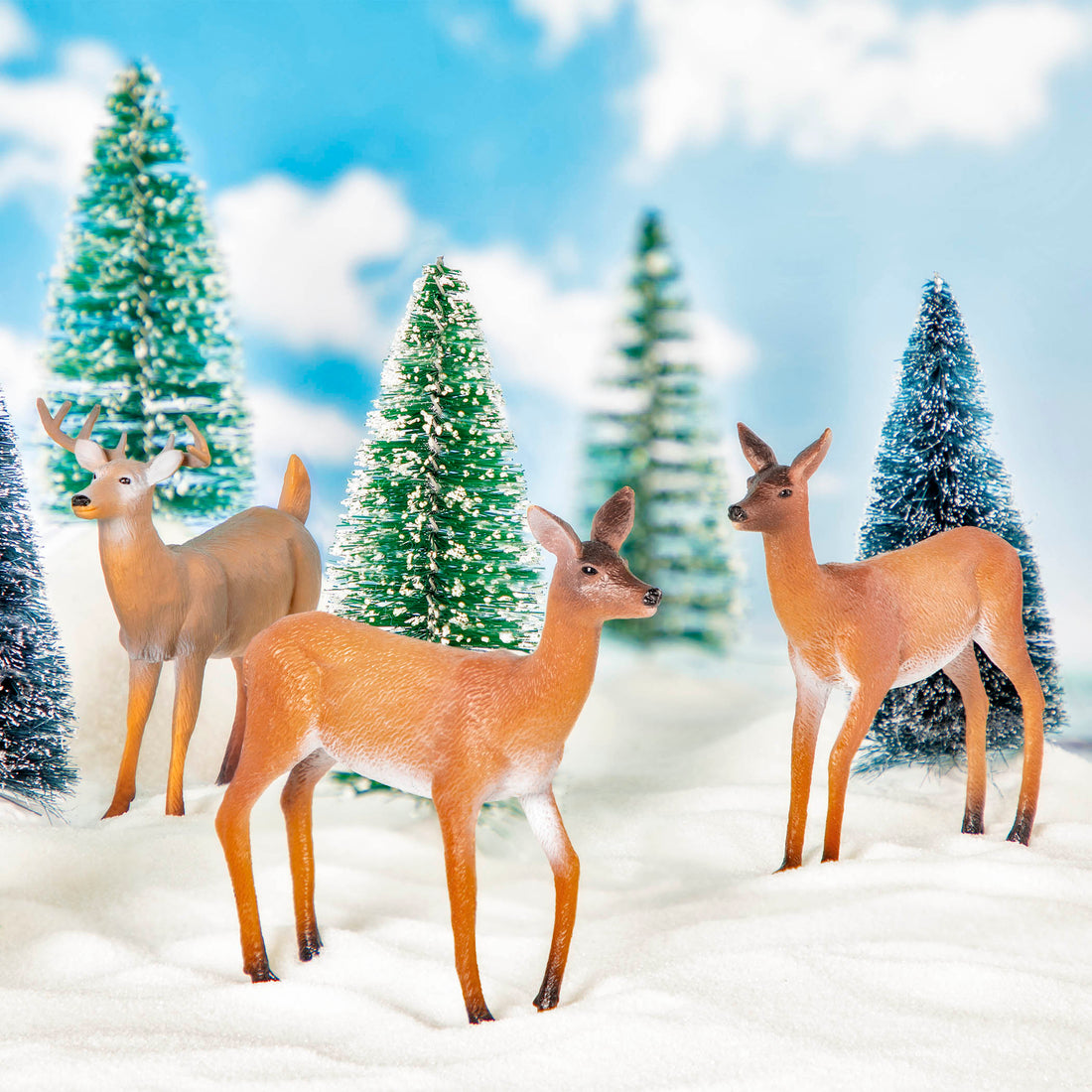 Three toy deer figurines in snow
