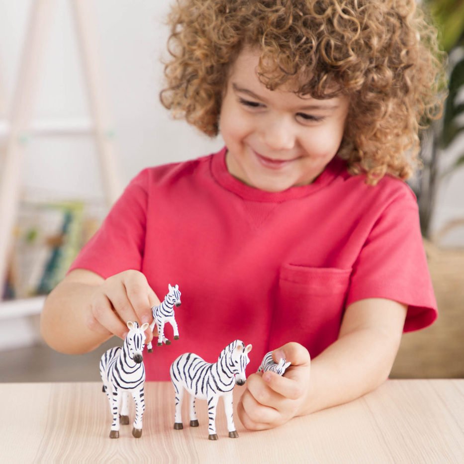 young boy playing with toy zebras.