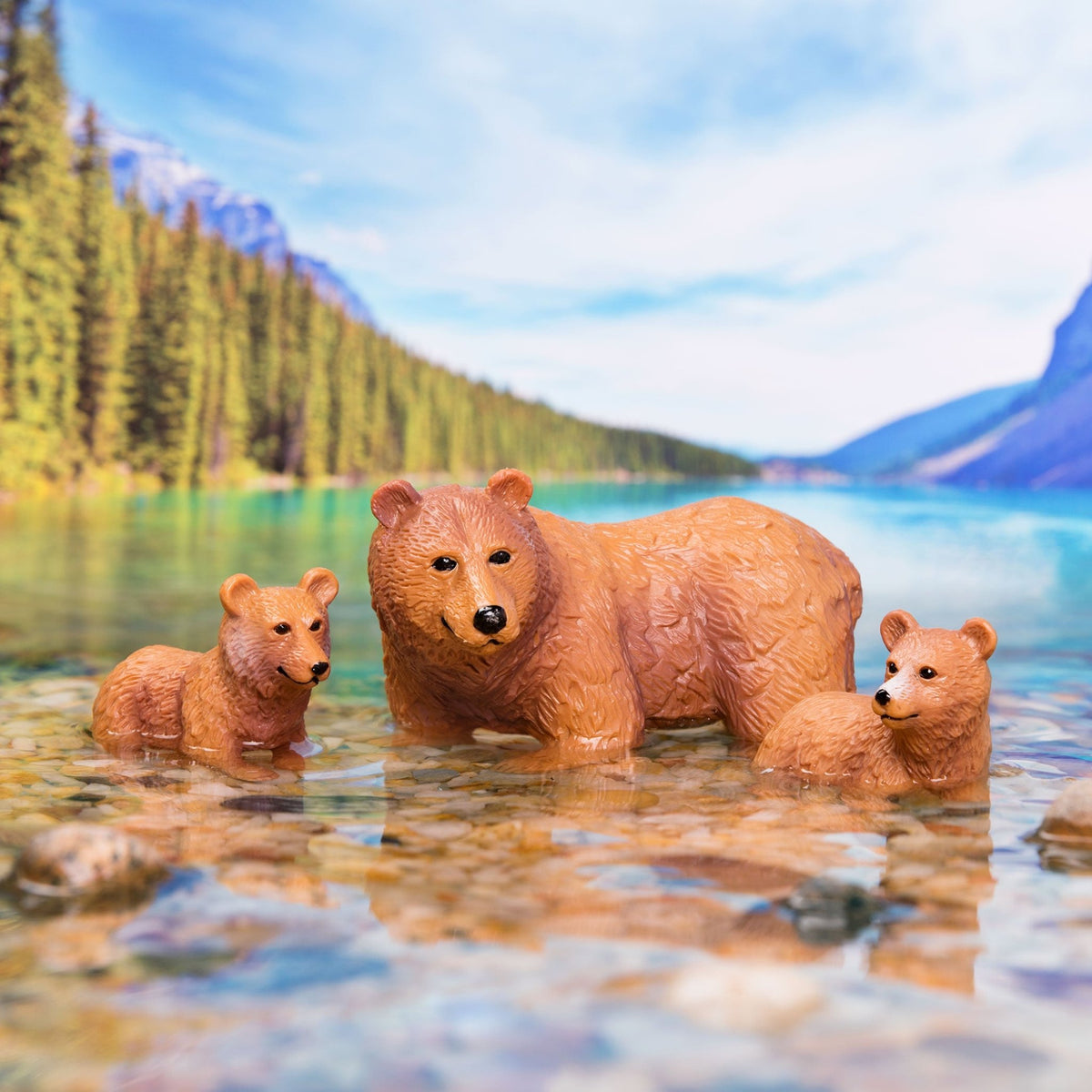 brown bears in water with mountains in background.