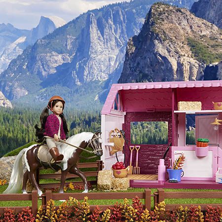 Mini doll riding a horse in the mountains.