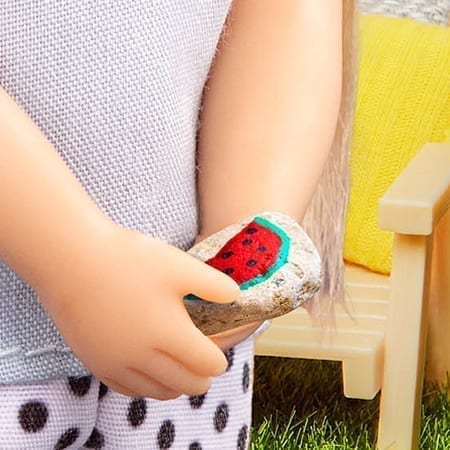 Doll holding painted rock.