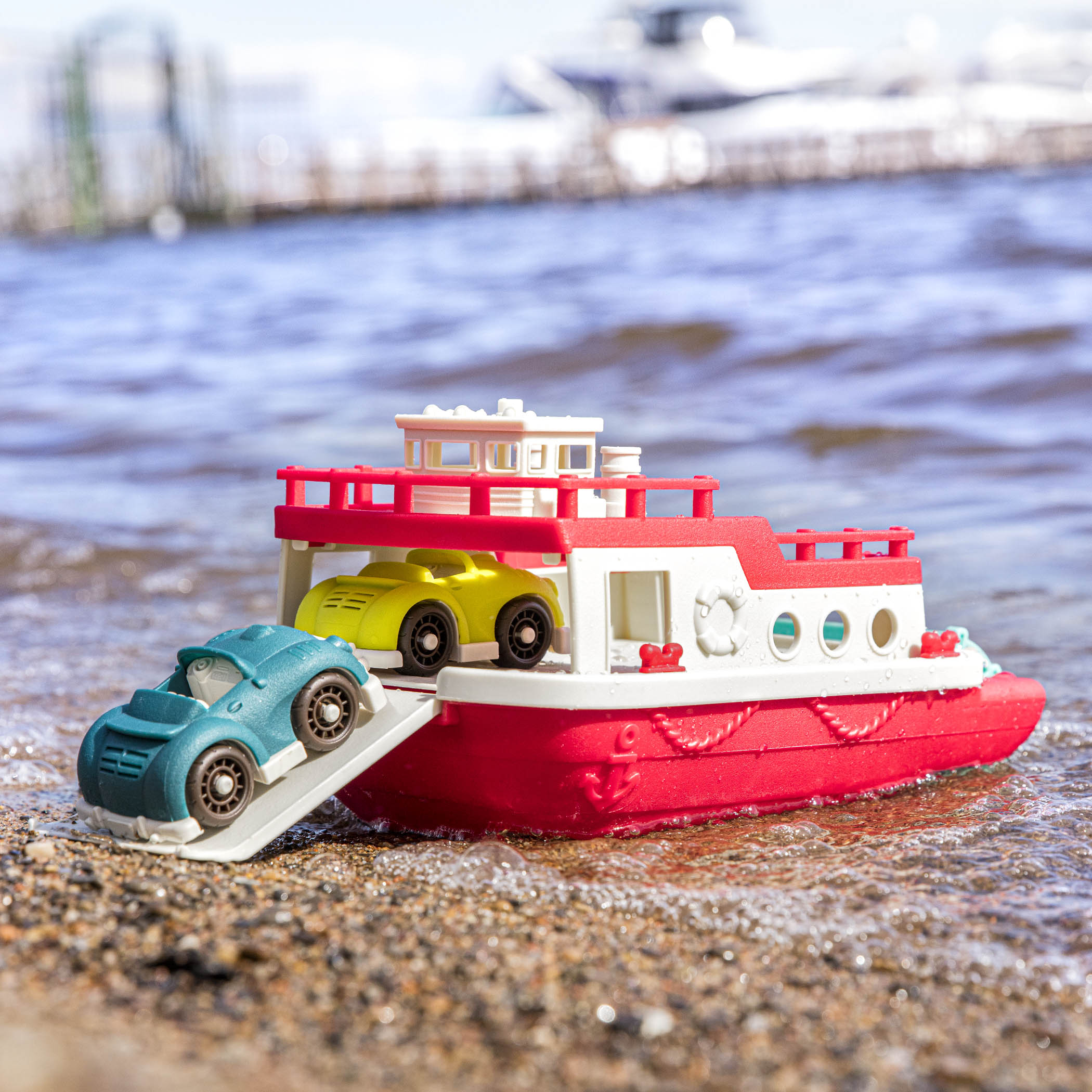 A ferry toy with the ramp down and 2 toy cars.