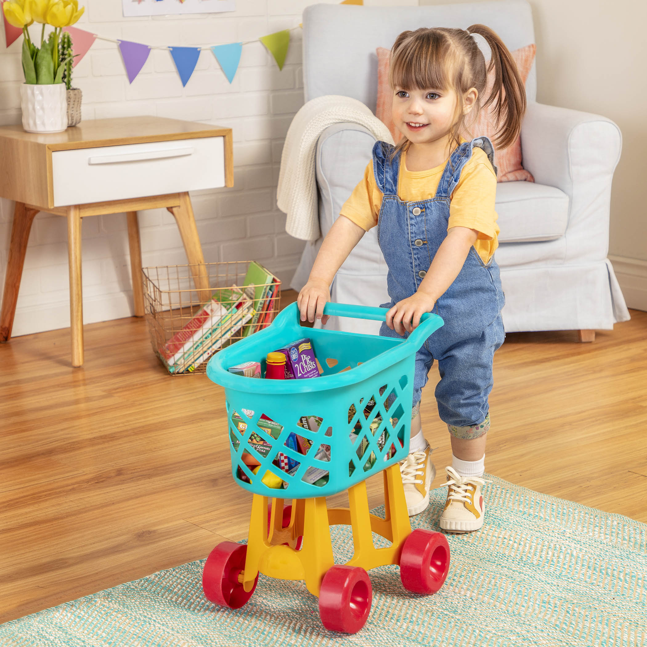 A blue, yellow, and red toy shopping cart complete with play food.