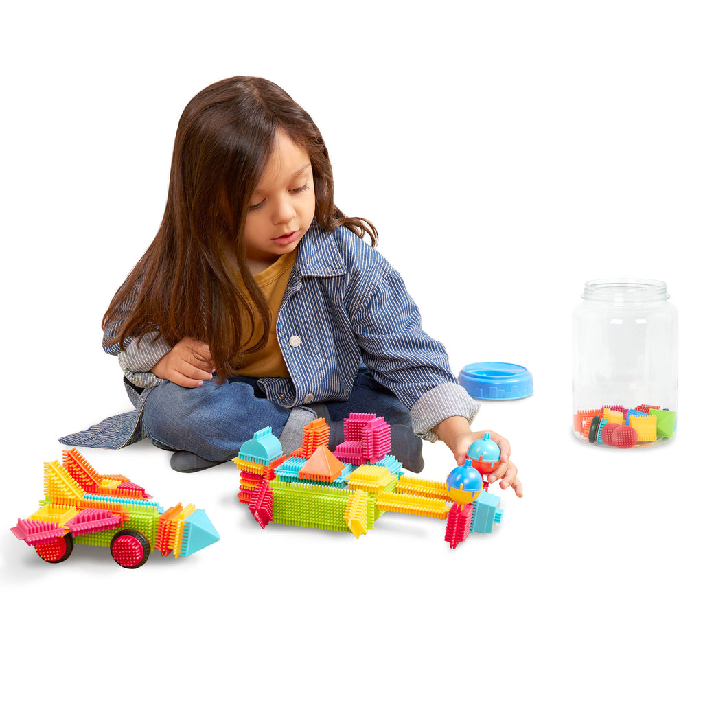 A colorful array of Bristle Blocks laid out so we can see all the pieces and the big reusable storage container.