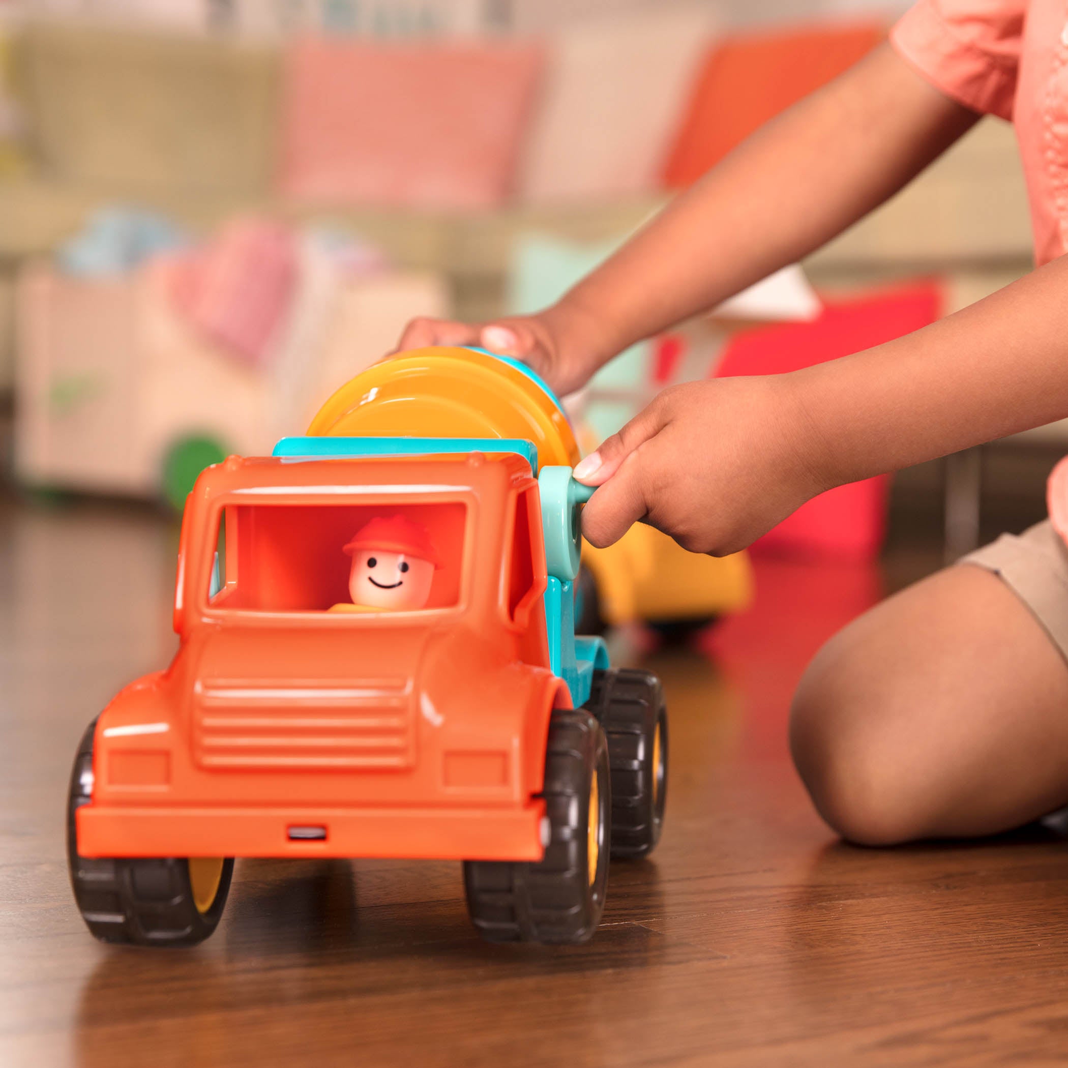 A toy cement mixing truck for kids and toddlers with a little driver figurine.