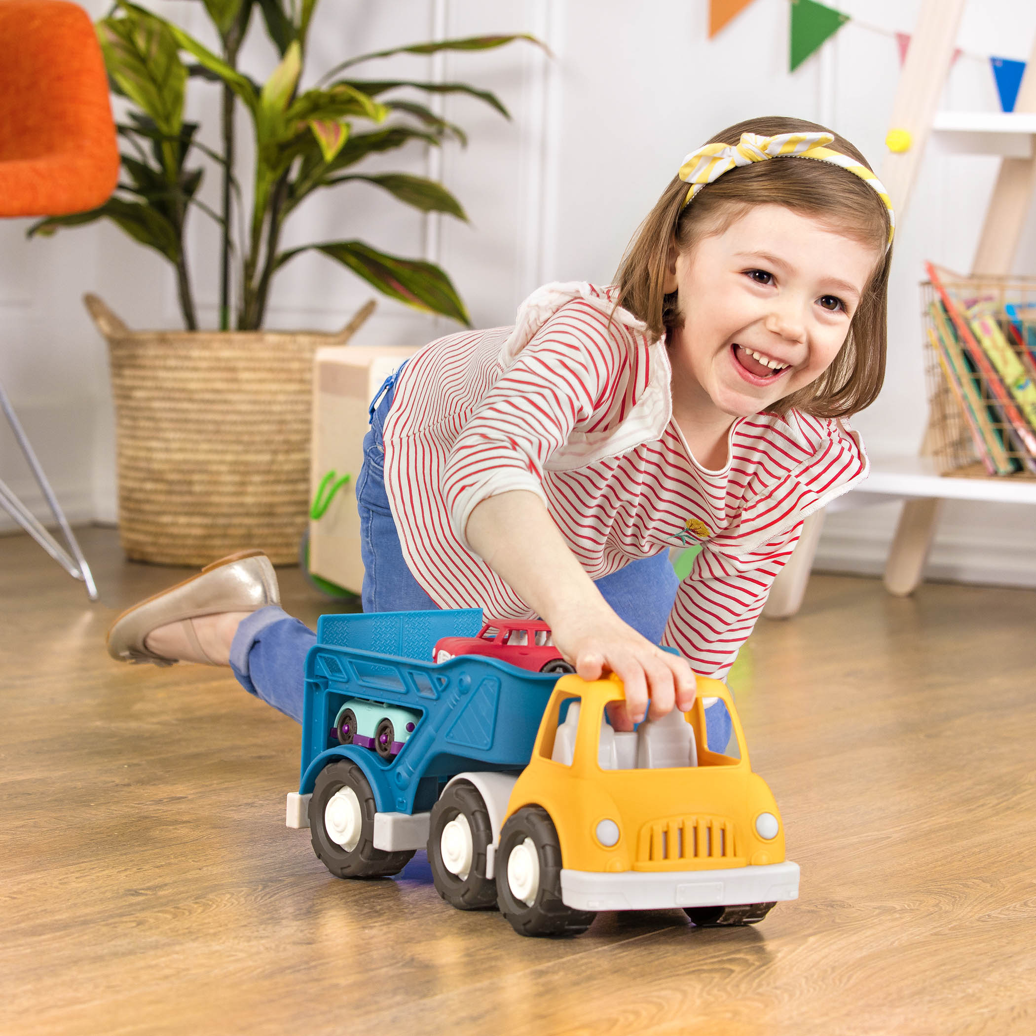 A yellow and blue car carrier truck with 2 toy cars aboard.